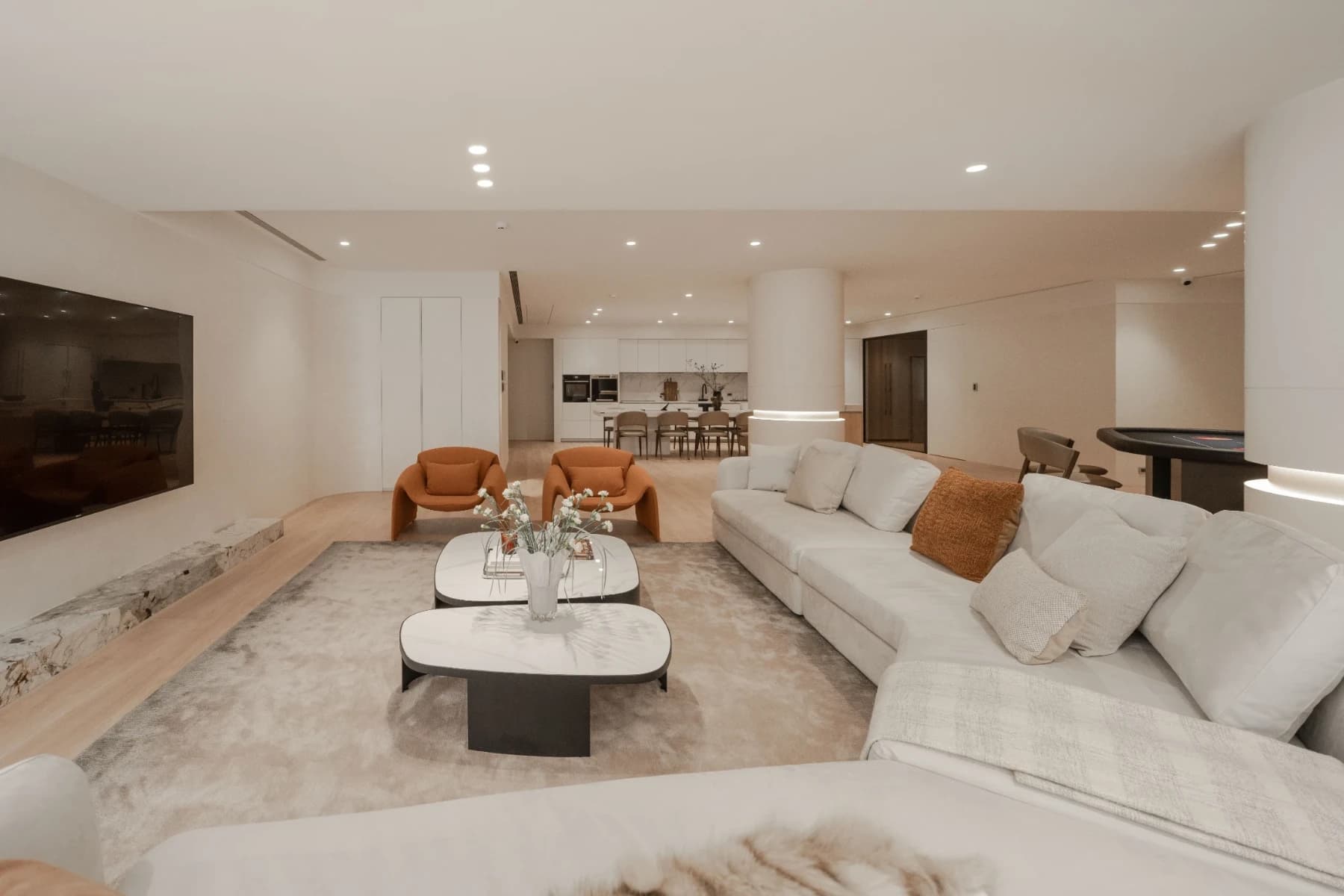 安頡建築操刀赫里翁 G House 豪宅客廳。現代 minimalist 風格的低飽和度沙發與不規則造型茶几，背景襯托溫潤木質壁板與溫馨立燈。