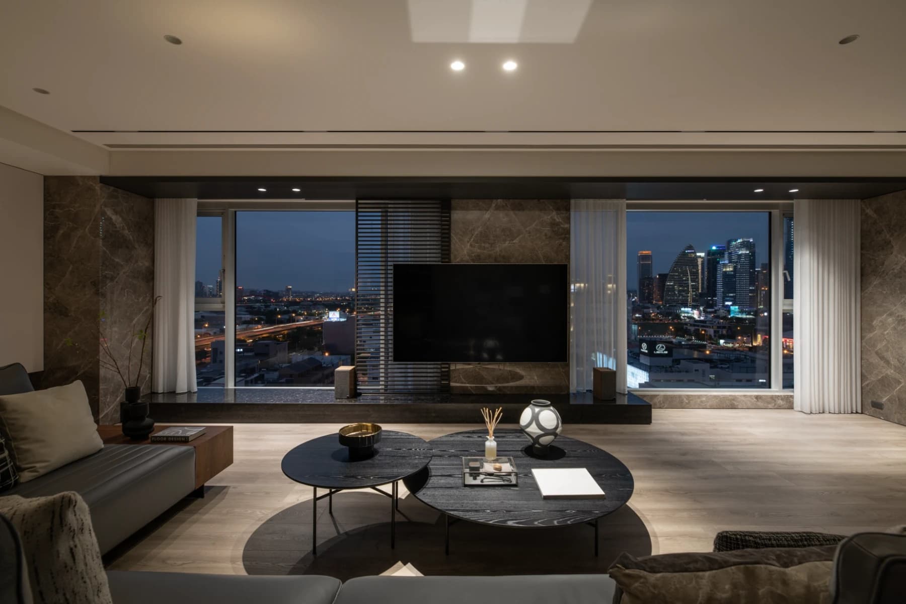 寶輝 CITY PARK C Residence ｜ AJA 安頡建築規劃的台中七期雙戶合併戶客廳夜景，沙發面向大面窗景與城市天際線，完美演繹高樓層景觀豪宅的流暢軸線與低調奢華基調。