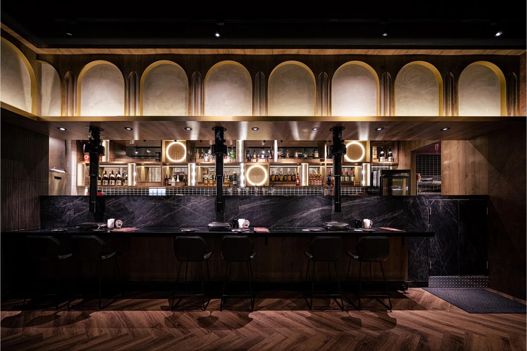 台中最肉 THE MEATIEST 燒肉餐酒館一樓吧台區，以小拱形造型、圓形裝飾燈與層次光影塑造成熟的餐飲氛圍