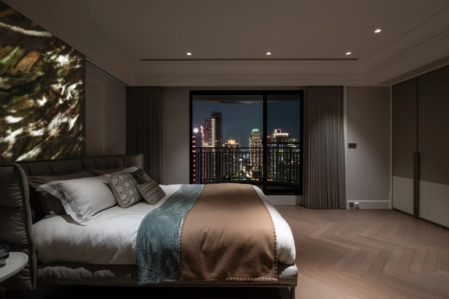 精銳市政廳主臥夜景以柔和照明、弧形界面與藍色石材床頭牆，讓住宅隨時間展現內斂而溫潤的感性情緒。