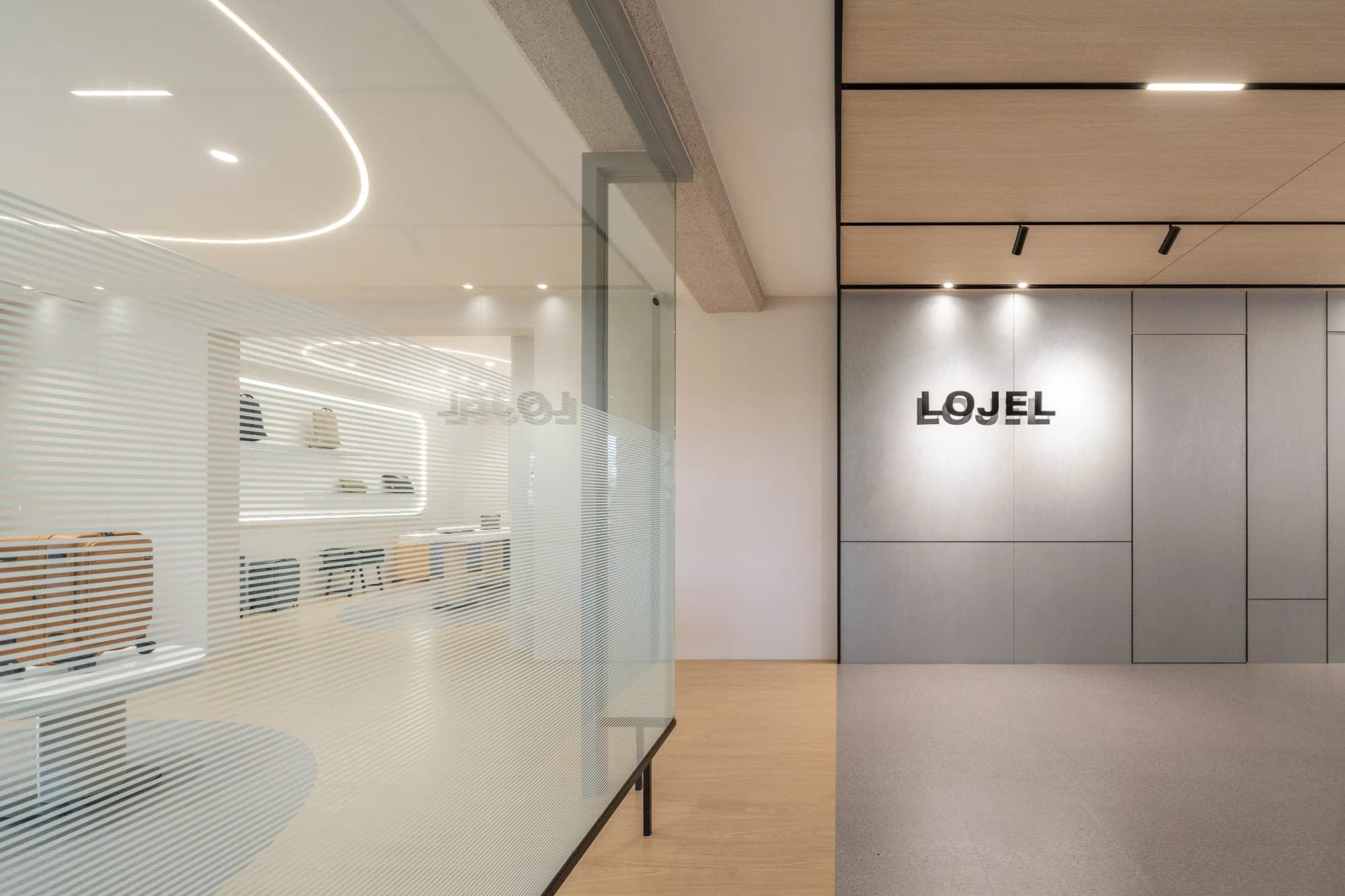 LOJEL 品牌形象牆與條紋玻璃隔屏，呈現 107 坪展示空間的通透層次