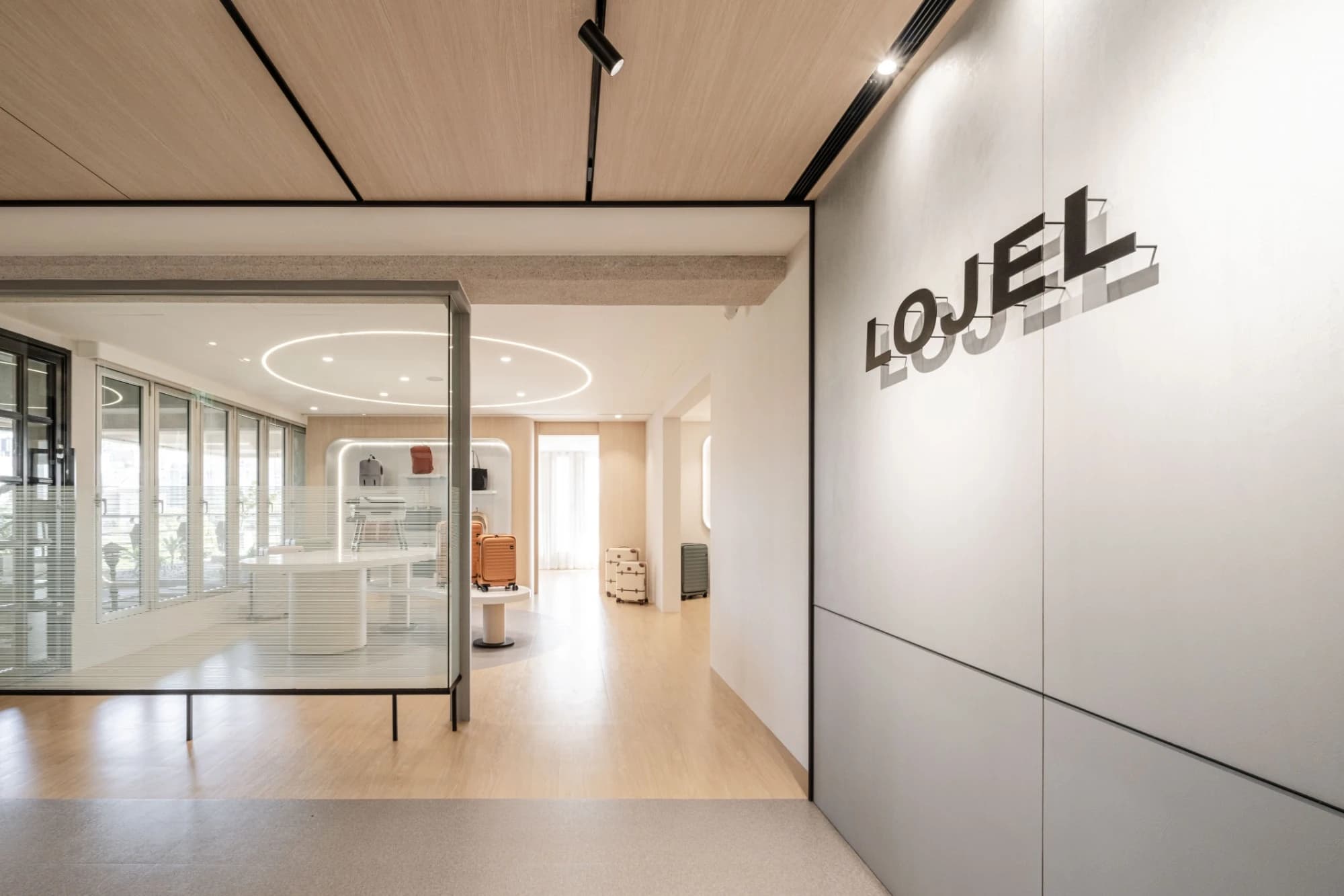 AJA安頡建築與室內設計規劃之 LOJEL 入口櫃檯區，灰色暗紋美耐板襯托品牌行李箱質感