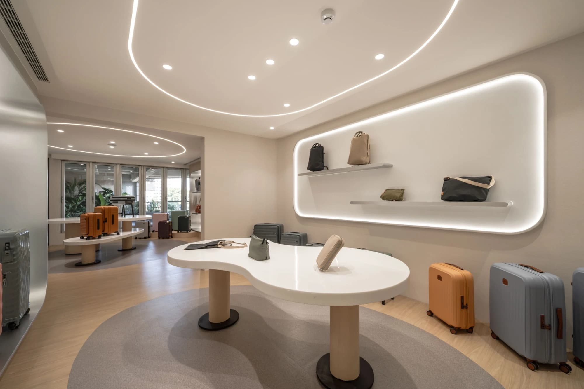 LOJEL 行李箱與包款展廳，採用流線型中島展台與嵌入式背光壁龕